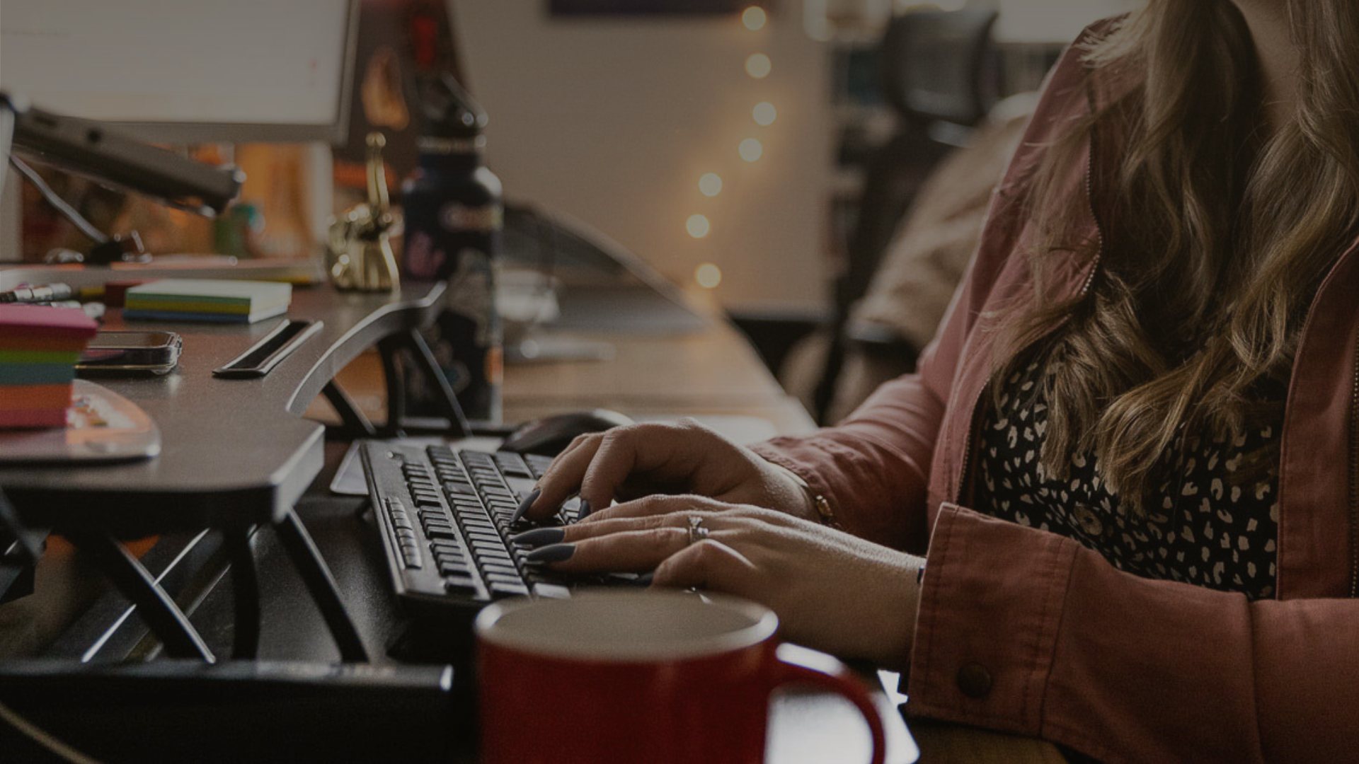 A computer monitor is on the left side of the screen with a woman looking at the screen and typing.