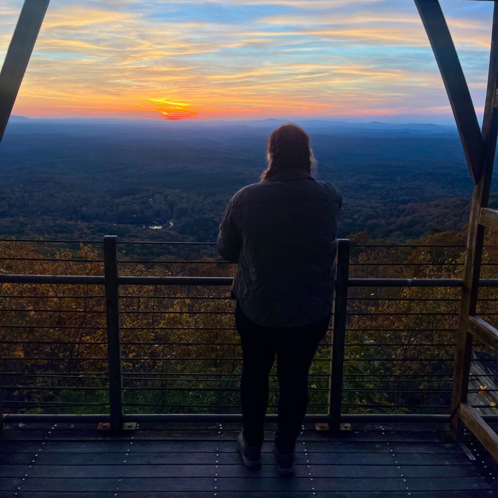 woman facing away from the camera facing toward a sunset