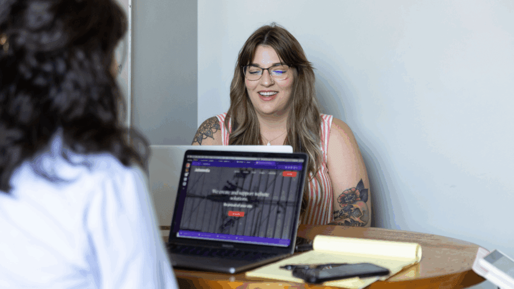 two women sitting at a table reviewing a website